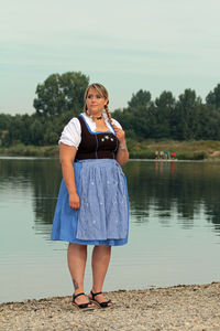 Young woman in dirndl standing at lakeshore