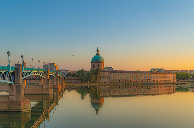 Reflection of building in river against clear sky