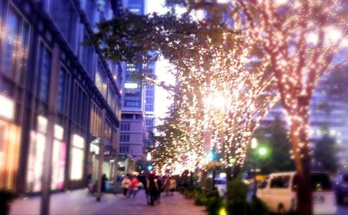 People walking on illuminated city at night