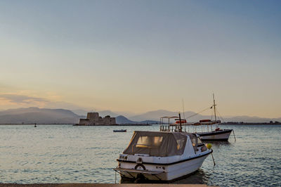 Sailboats moored on harbor against sky during sunset