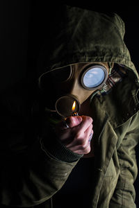 Close-up of portrait of woman holding burning lighter against over black background