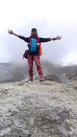 Full length of man with arms raised against sky