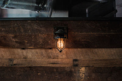 View of illuminated lighting equipment on wooden wall