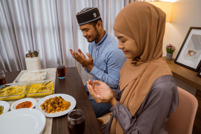 Couple praying while having food at home