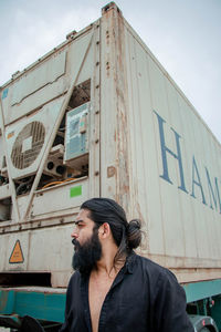 Bearded man with hair bun standing against truck