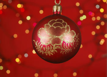 Close-up of red christmas bauble against lights