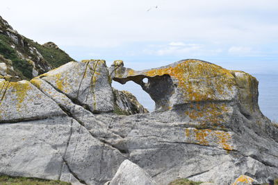 Rock formation by sea against sky