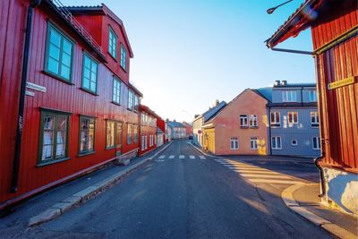 Road amidst buildings against clear sky