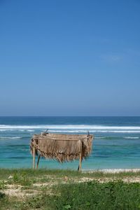 Wooden posts on beach against clear blue sky