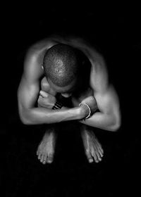 High angle view of young man crouching over black background