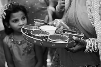 Midsection of woman holding plate with bowls during ceremony