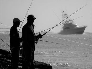 Man fishing in sea against sky