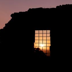 Low angle view of silhouette tree and building against sky during sunset