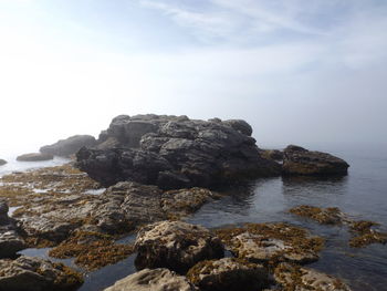 Rock formation in sea against sky