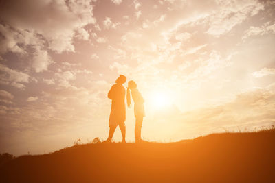 Silhouette couple standing against sky during sunset