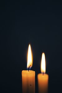 Close-up of burning candle against black background