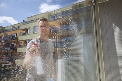 Man using mobile phone by window in city