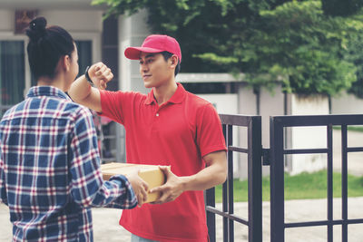 Man delivering package to female customer at gate