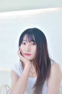 Portrait of young woman sitting on window