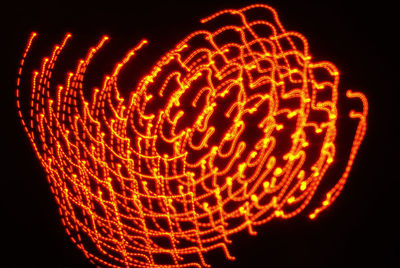 Low angle view of illuminated lights against black background