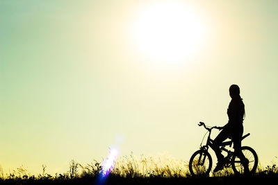 Silhouette woman with bicycle against sky