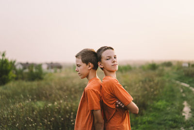 Funny twin brother boys playing outdoors on field at sunset.