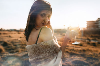 Young woman with a wine glass in a field at sunset