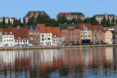 Reflection of buildings in lake against clear sky