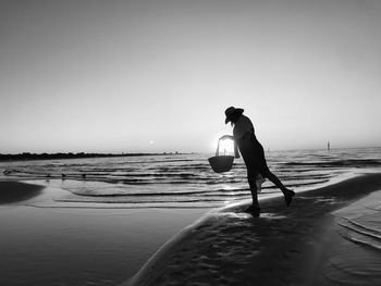 Silhouette man standing on beach against clear sky