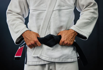 Midsection of man standing against black background