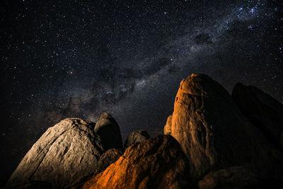 Low angle view of rock formations against star field at night