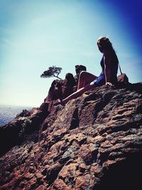 Woman resting on rock formations at mountain on sunny day