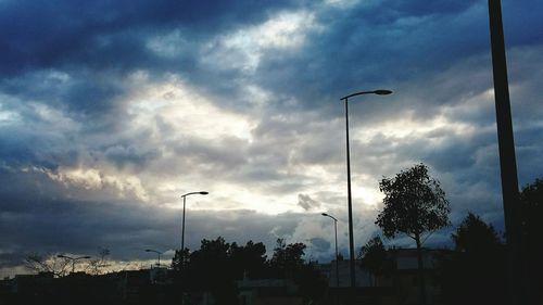 Low angle view of silhouette trees against cloudy sky