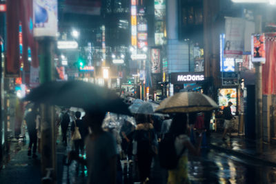 People walking on illuminated street at night