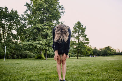 Woman bending while standing on grassy field