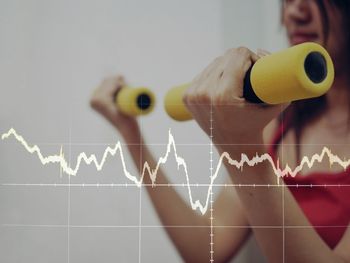 Digital composite image of pulse trace against mature woman exercising at home