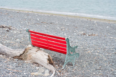 Red park bench seat on the beach