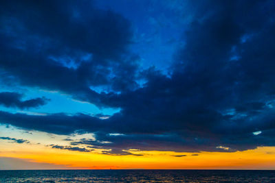 Scenic view of sea against dramatic sky during sunset