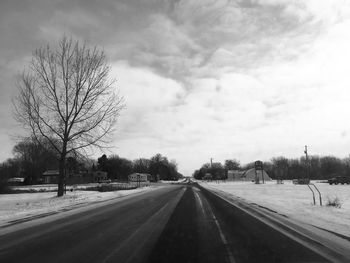 Road amidst bare trees against sky