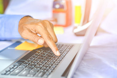 Cropped hand of businessman using laptop