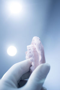 Close-up of hand holding dental mold against illuminated lights