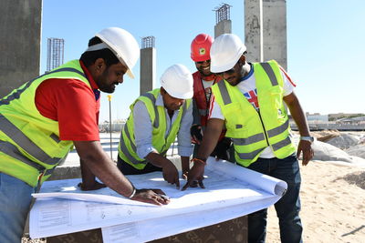 Young man with arms outstretched standing at construction site