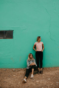 Smiling friends spending leisure time against wall