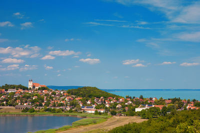 Scenic view of town by sea against sky