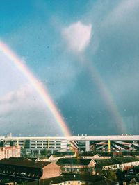 Rainbow over buildings in city against sky