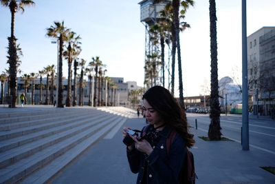 Woman photographing while standing on city street