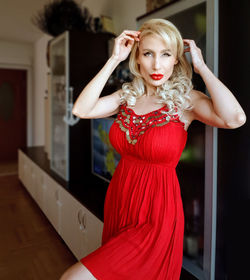 Portrait of a young woman standing against red wall