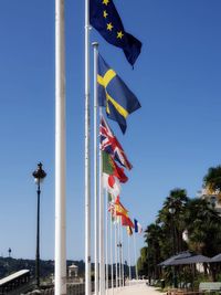 Low angle view of flags against clear blue sky