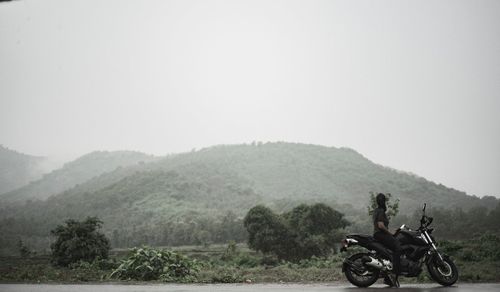 Man riding bicycle on mountain against clear sky