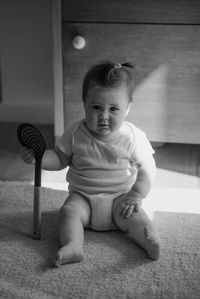 Cute baby girl sitting on carpet at home